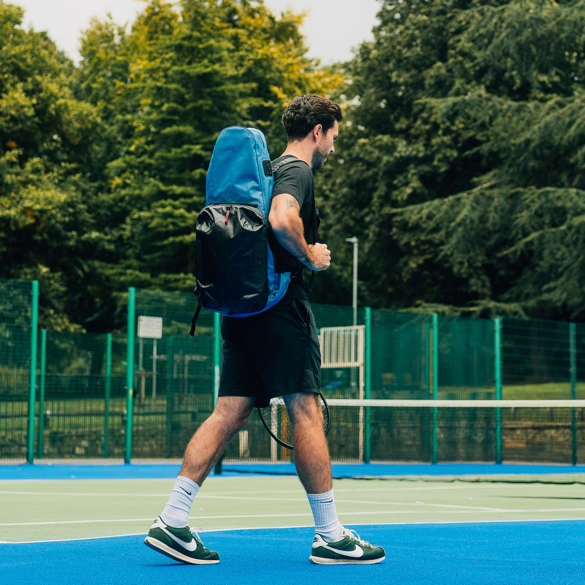 A player crouching courtside beside the Mint Green Racquet Bag Voyager
